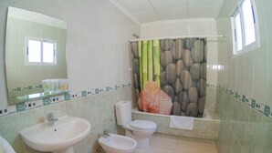 A bathroom with a sink, bidet, toilet, and a shower curtain with a bamboo pattern. - Hostal Meseguer (Elche)