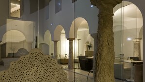 A modern interior with stone columns, arched ceilings, and a seating area with a unique perforated sculpture. - Hotel Viento10 (Córdoba)