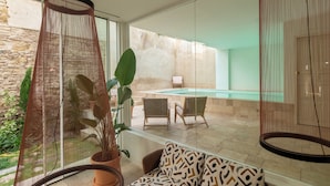 A modern interior with a glass partition, a pool, and outdoor seating. - Hotel Viento10 (Córdoba)