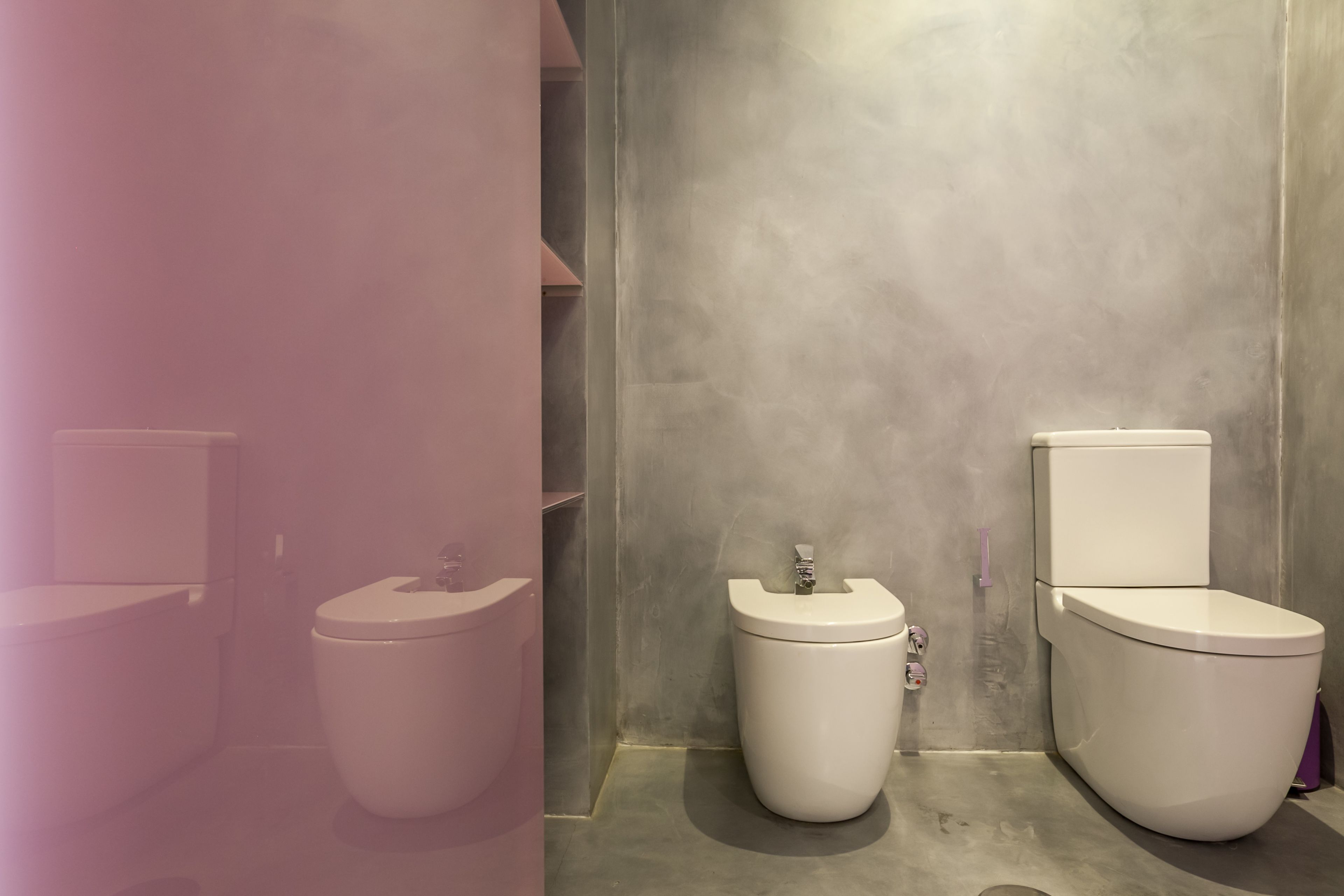 A modern bathroom with two toilets, a sink, and a shower area.