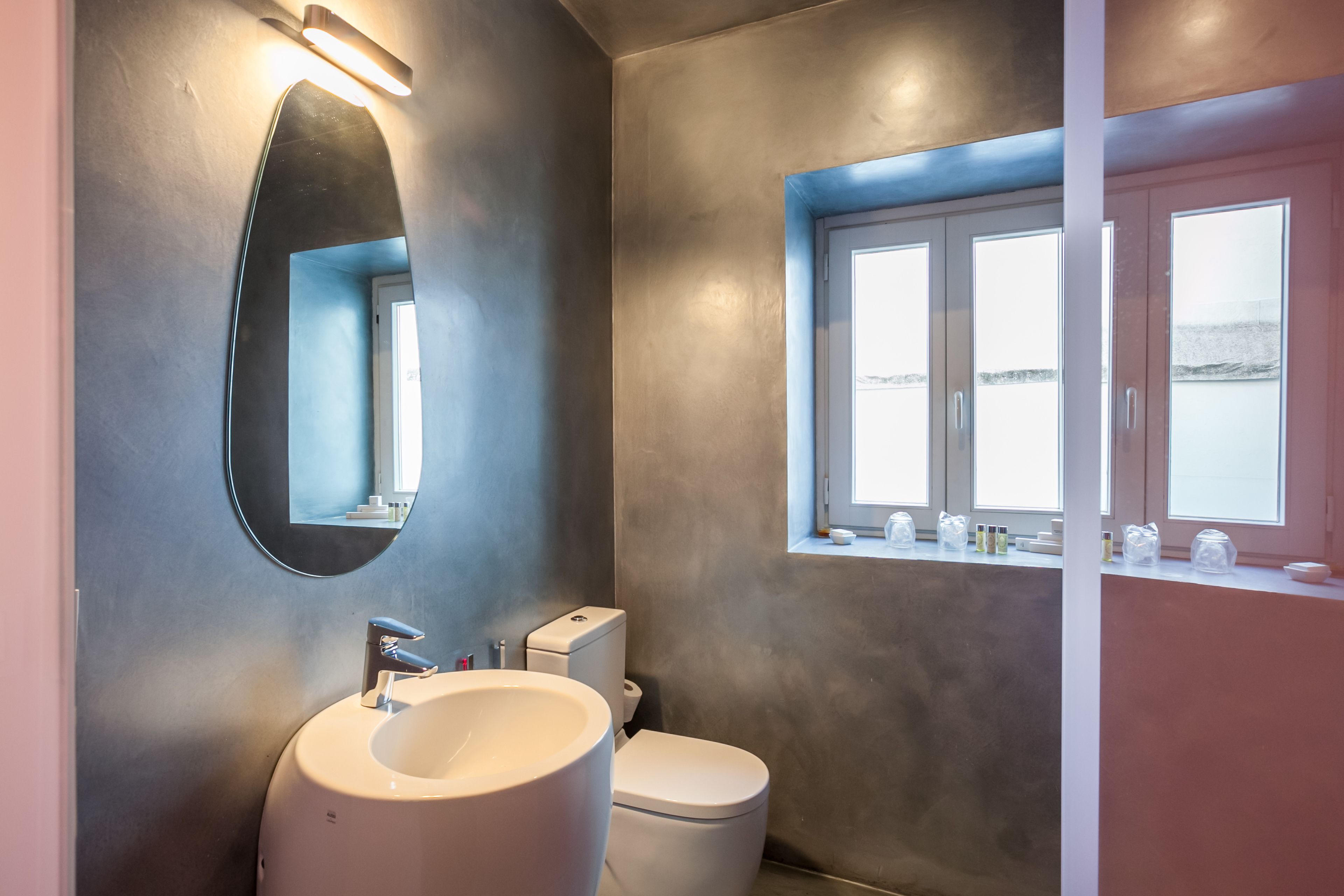Ein modernes Badezimmer mit rundem Spiegel, Waschbecken und Toilette.