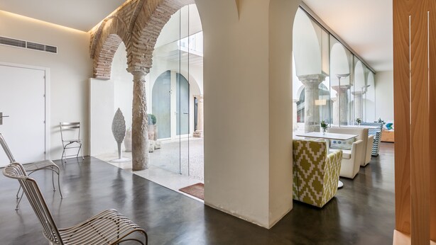 A modern interior with a central open space, stone arches, and a seating area with patterned cushions. - Hotel Viento10 (Córdoba)