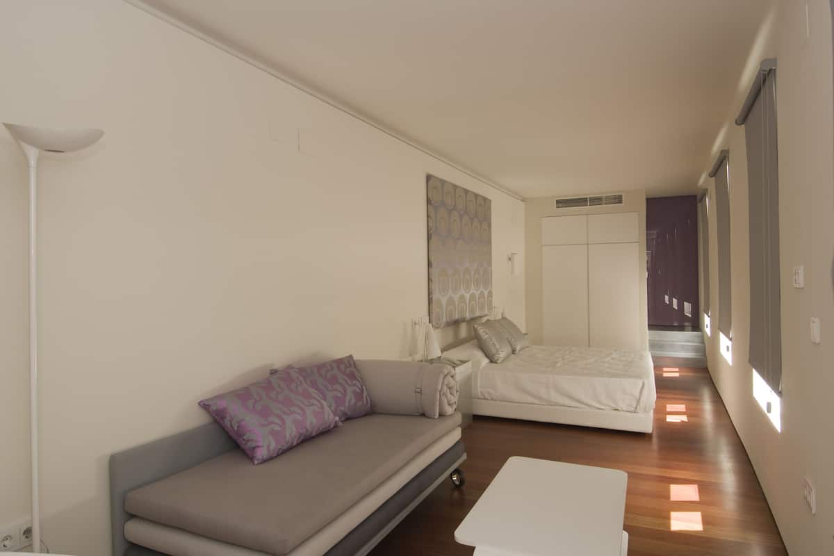 Una sala de estar moderna y minimalista con sofá, cama y una mesita de centro.