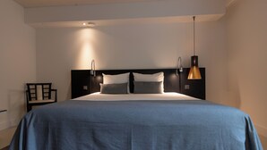 Un dormitorio moderno con una cama grande, una mesita de noche y una lámpara de pared.