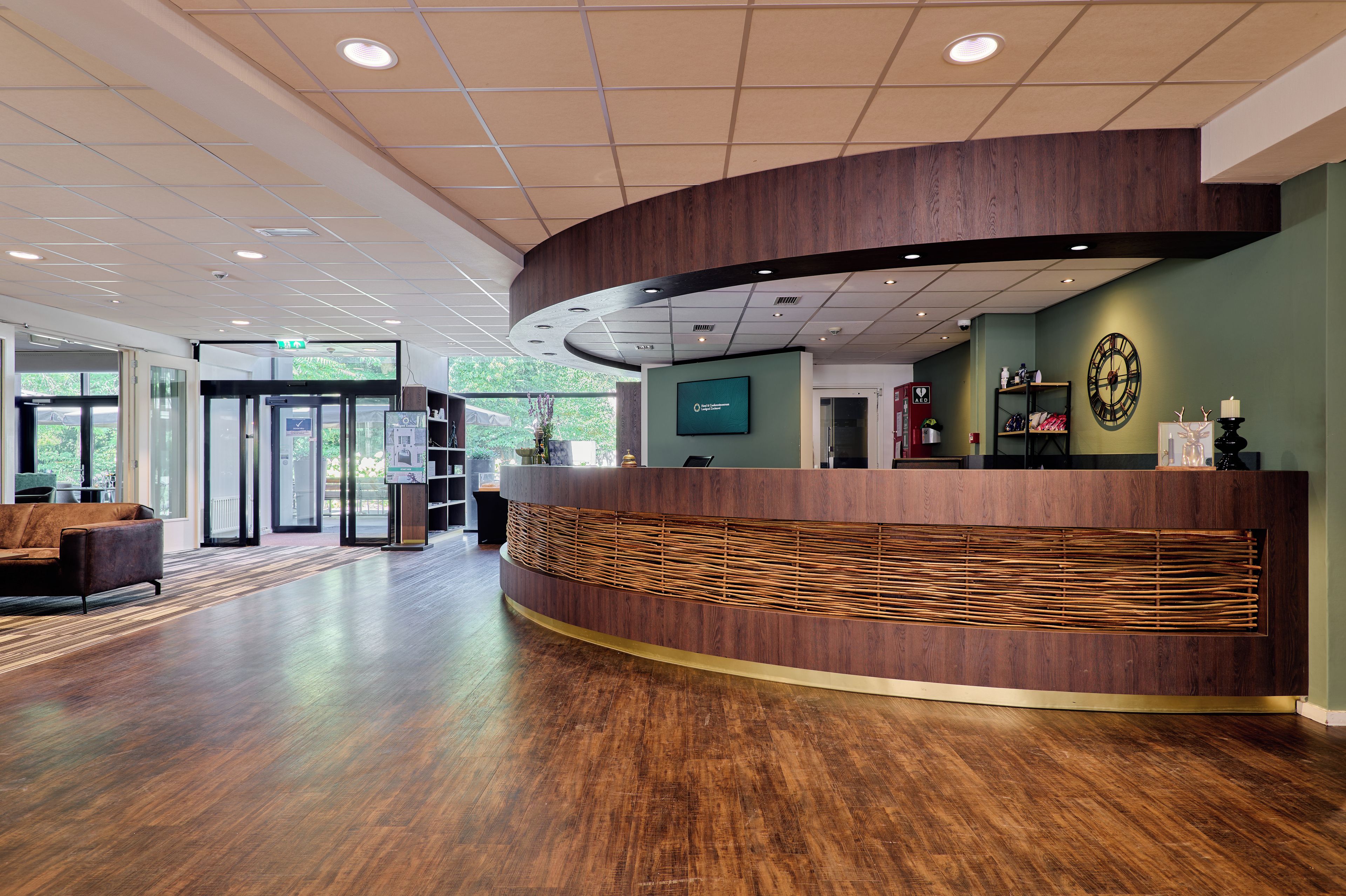 A reception area with a curved reception desk, a clock, and a view of the outdoors.