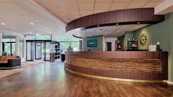 A reception area with a curved reception desk, a clock, and a view of the outdoors.