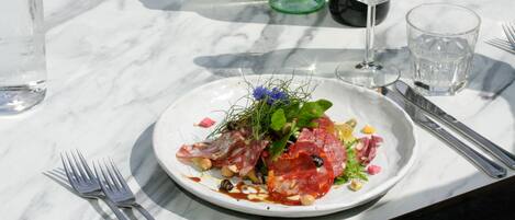Une table à manger avec une assiette de nourriture, une bouteille de vin et un verre de vin.