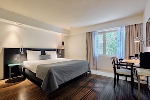 Un dormitorio moderno con cama, mesita de noche, escritorio, silla y una ventana con cortinas.