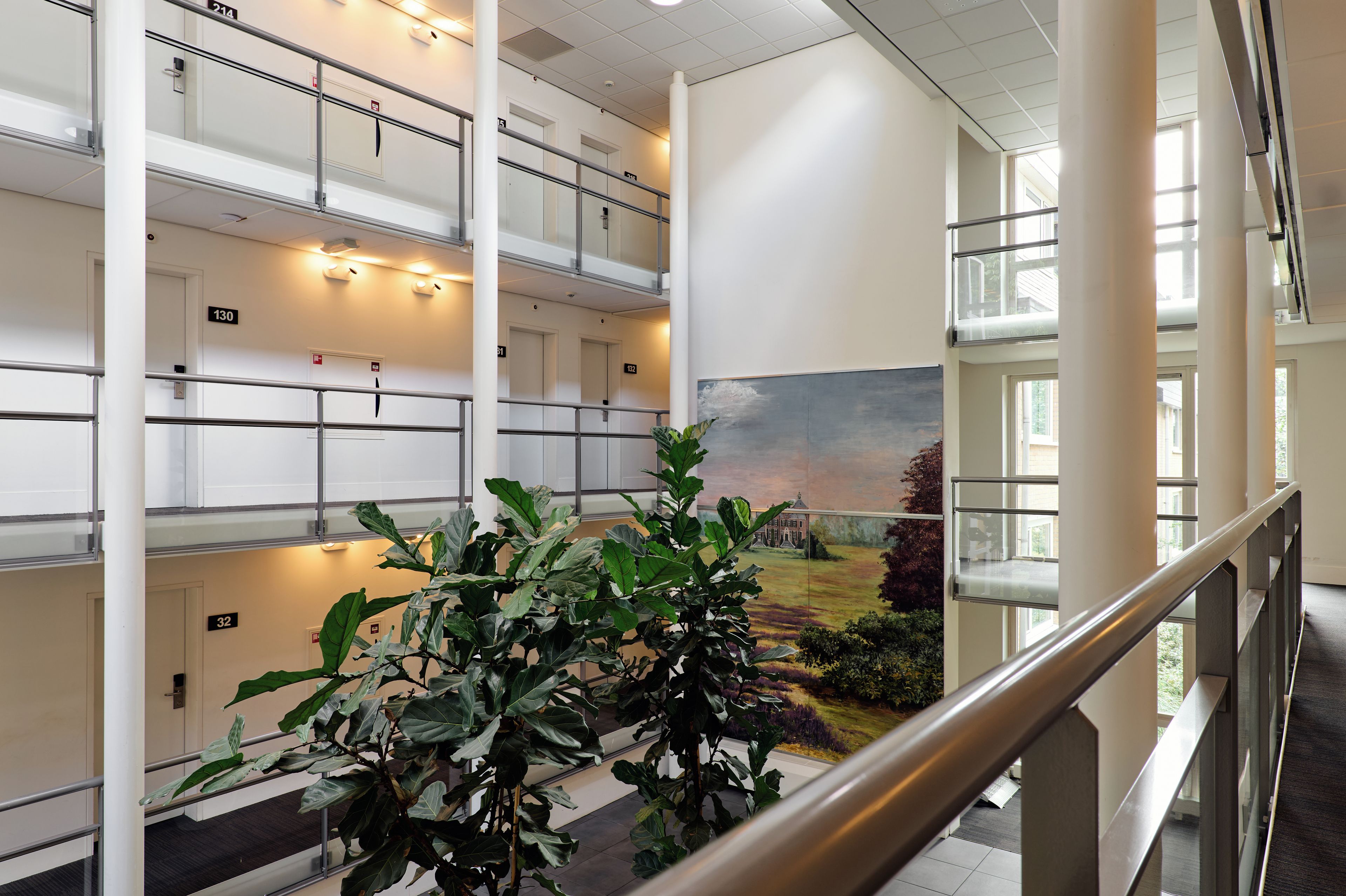 Ein mehrgeschossiges Interieur mit Blick auf eine angelegte Grünfläche durch eine Glaswand.