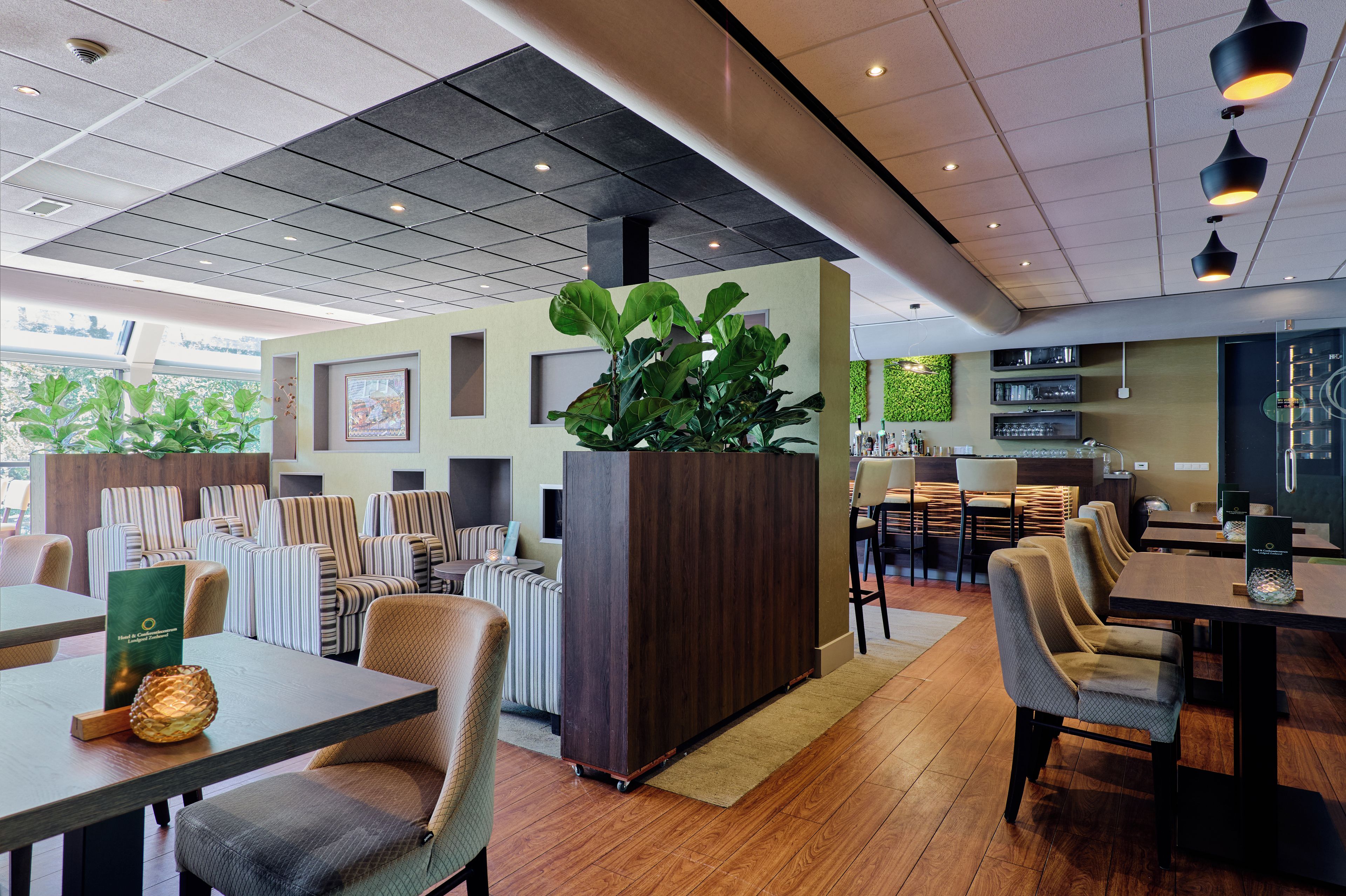 Un interno di ristorante moderno con sedie a righe, una pianta centrale e un'area bar.