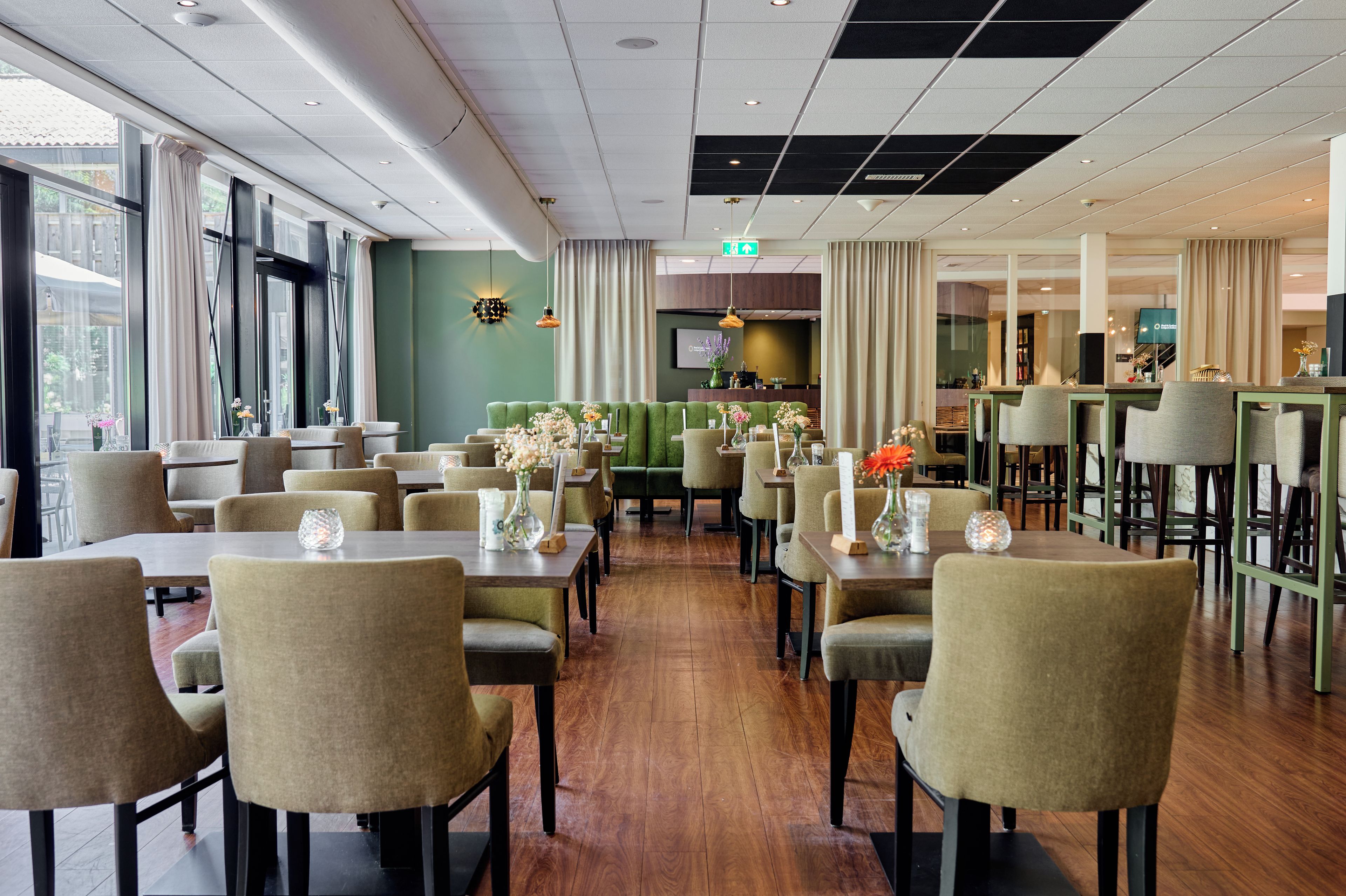 A restaurant with multiple tables and chairs, a bar area, and a green seating section.