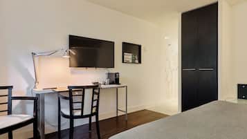 A modern bedroom with a bed, a desk with a chair, a TV, and a wardrobe.