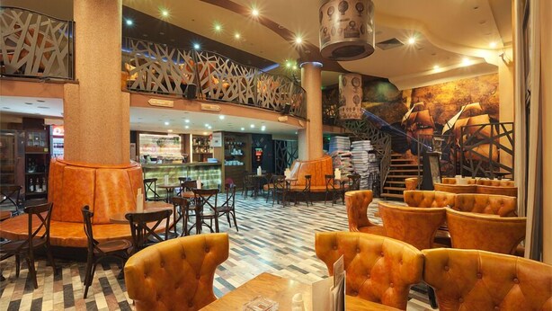 Un hall de hotel con mostrador de recepción, zona de estar y una escalera.
