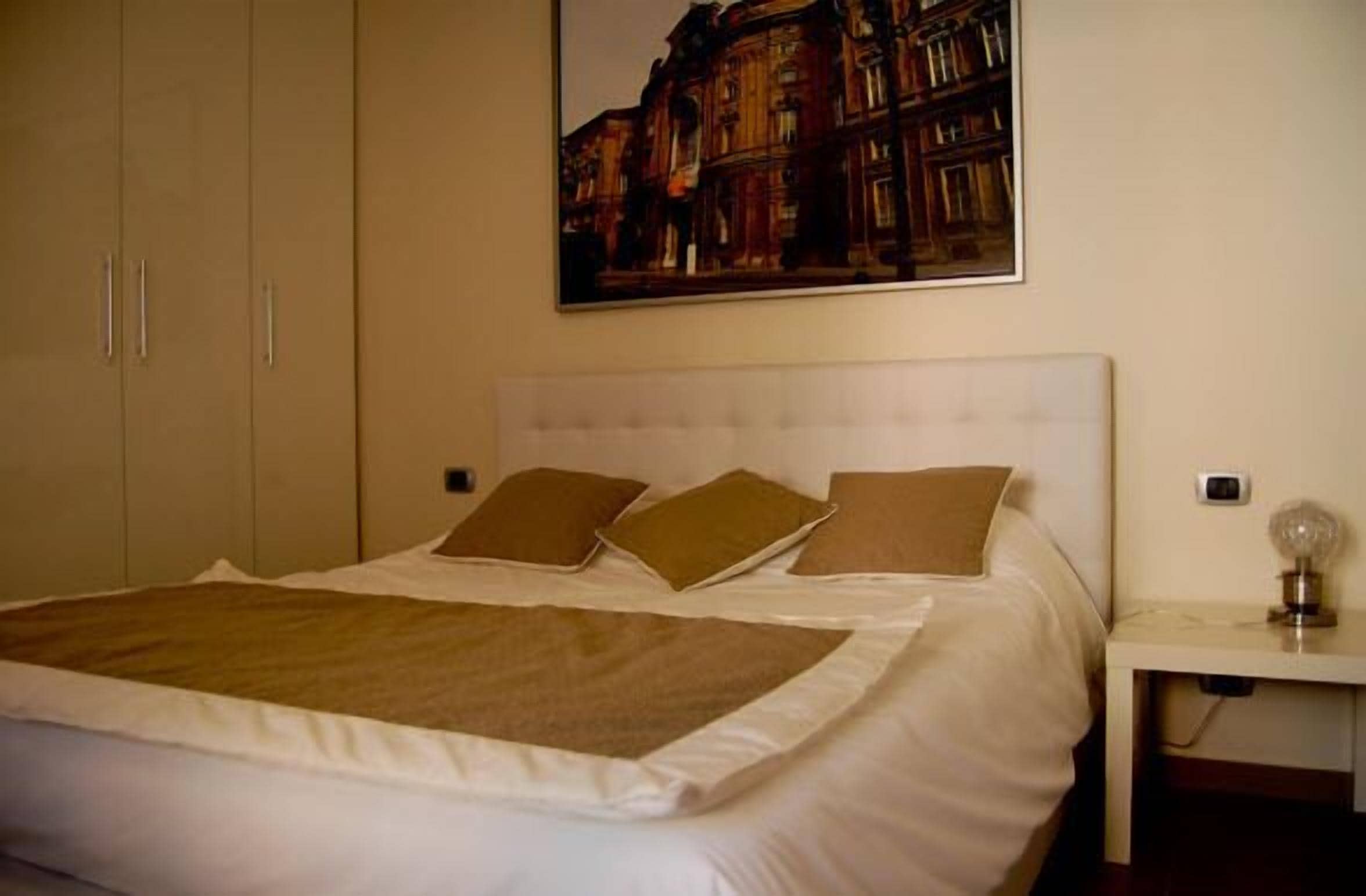 A bedroom with a large bed, a headboard, and a nightstand.