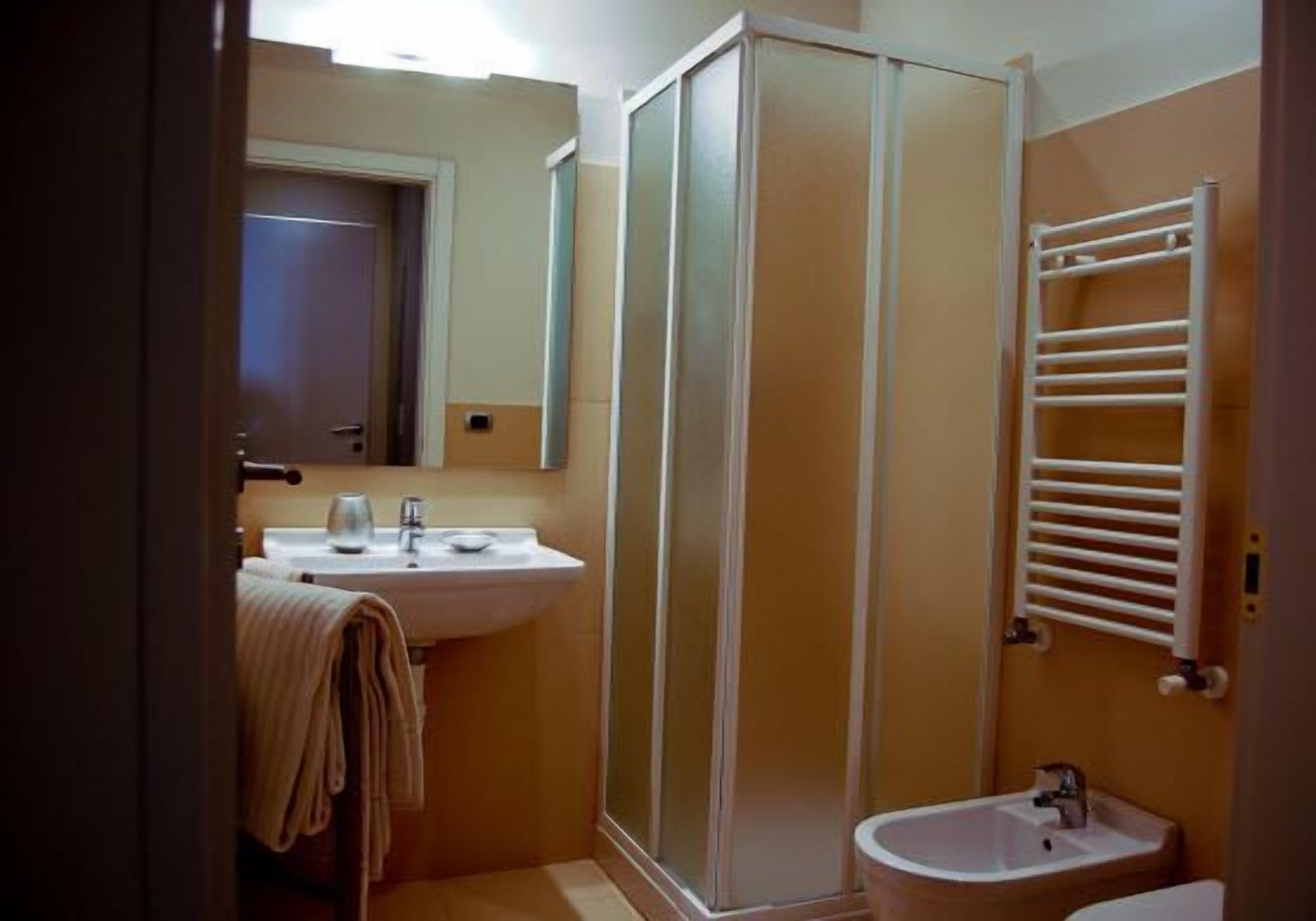 A compact bathroom with a shower enclosure, a sink, and a towel rack.