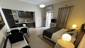 Une chambre d’hôtel moderne équipée d’un lit, de tables de chevet, d’un bureau et d’une kitchenette.