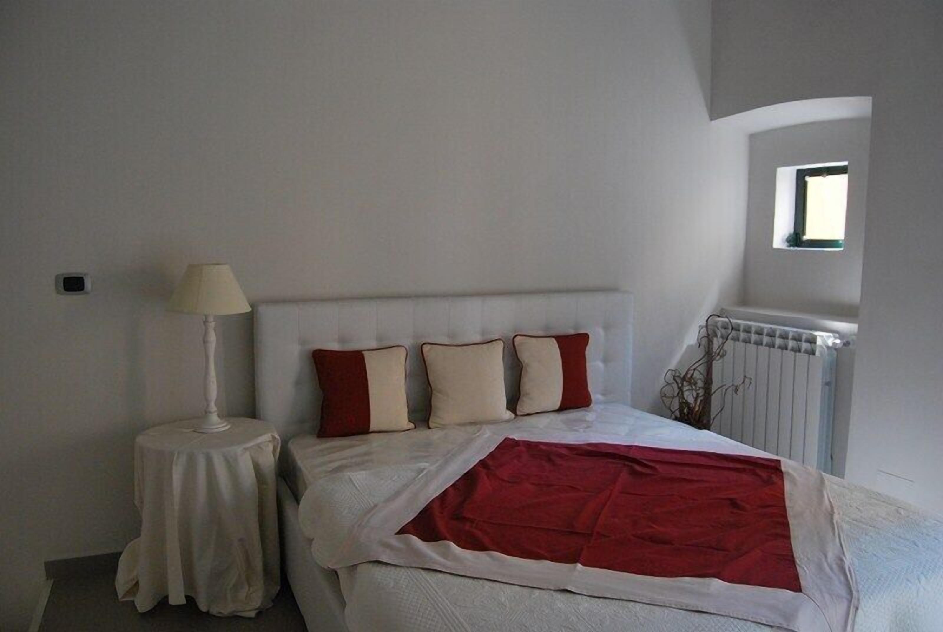 A bedroom with a bed, a bedside table with a lamp, and a radiator.