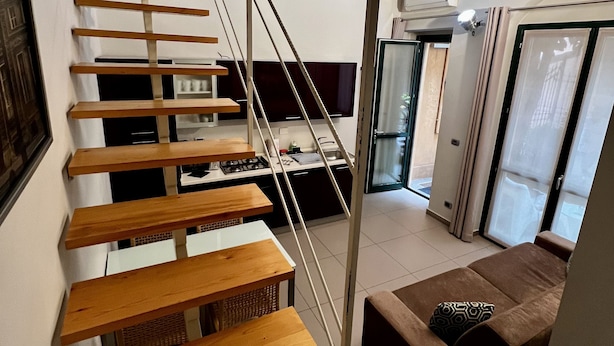Un intérieur moderne avec un escalier en bois, un coin cuisine et un espace salon avec un canapé.
