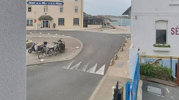 Een hotel met een bord waarop staat 'Hotel de la Mer et de la Plage', een parkeerplaats met fietsen en uitzicht op zee.