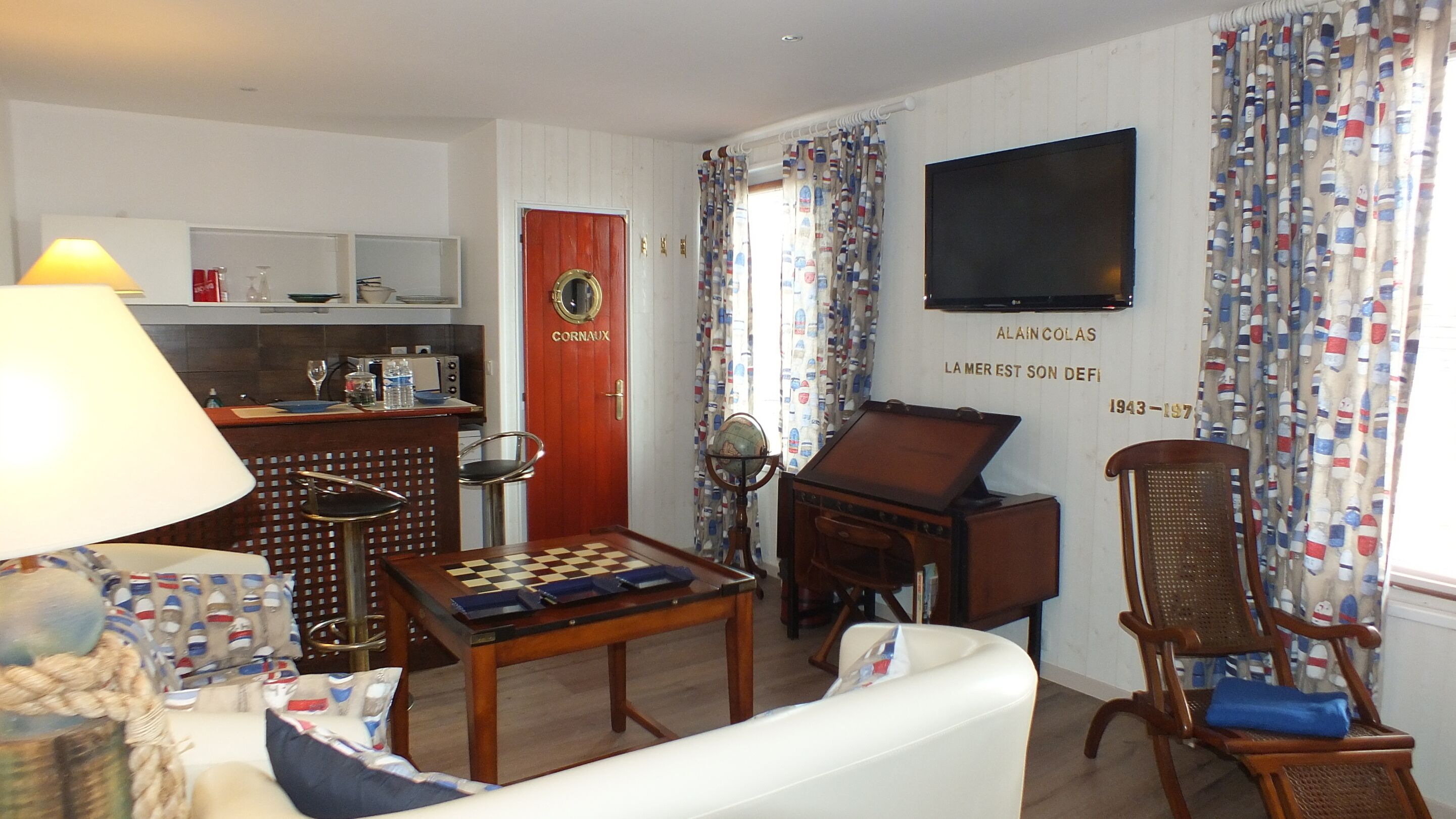Ein Wohnzimmer mit Schachbrett, Globus, Holzschrank und Fernseher an der Wand.