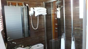 A modern bathroom with a glass-enclosed shower, a toilet, a sink, and a mirror.