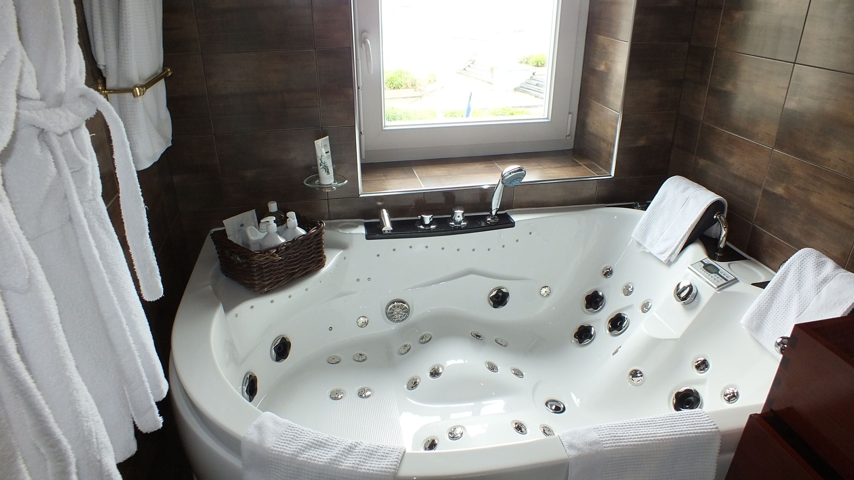 Une salle de bain avec une grande baignoire, une fenêtre et un porte-serviettes.