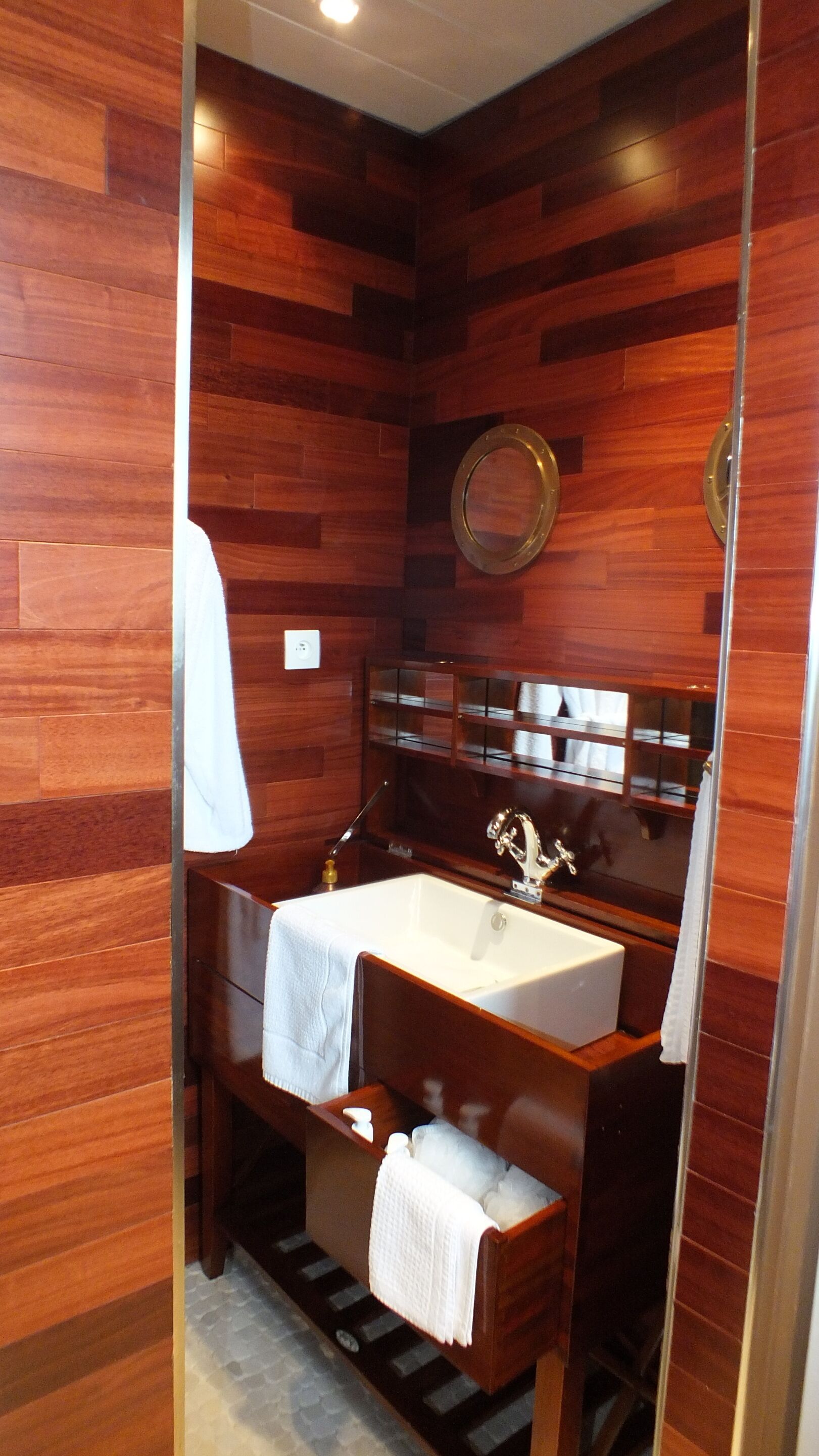 A bathroom with wooden paneling, a white sink, a mirror, and a towel rack.