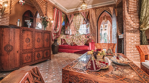 Un intérieur traditionnel avec un canapé, un meuble en bois et une table recouverte d’une nappe décorative.