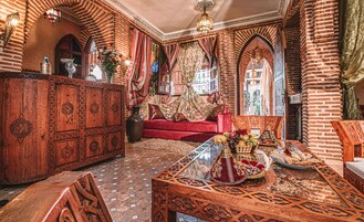 Un interior tradicional con un sofá, un aparador de madera y una mesa con un mantel decorativo.