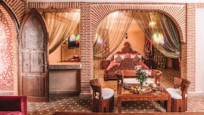 Un intérieur marocain traditionnel avec un coin repas, un canapé et un téléviseur.