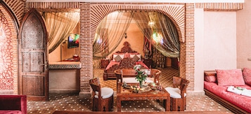 Un interior tradicional marroquí con una zona de comedor, un sofá y un televisor.