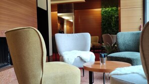 A modern interior with a round table, two chairs, and a potted plant.
