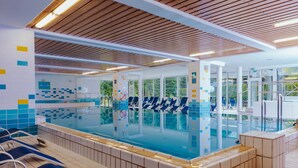 A swimming pool with blue and white tiled walls, wooden ceiling, and a tiled floor.