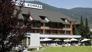 A hotel with a sign reading "HOTEL KOMPAS" and a balcony with outdoor seating.
