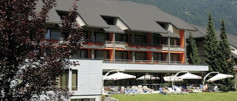 A hotel with a sign reading "HOTEL KOMPAS" and a balcony with outdoor seating.