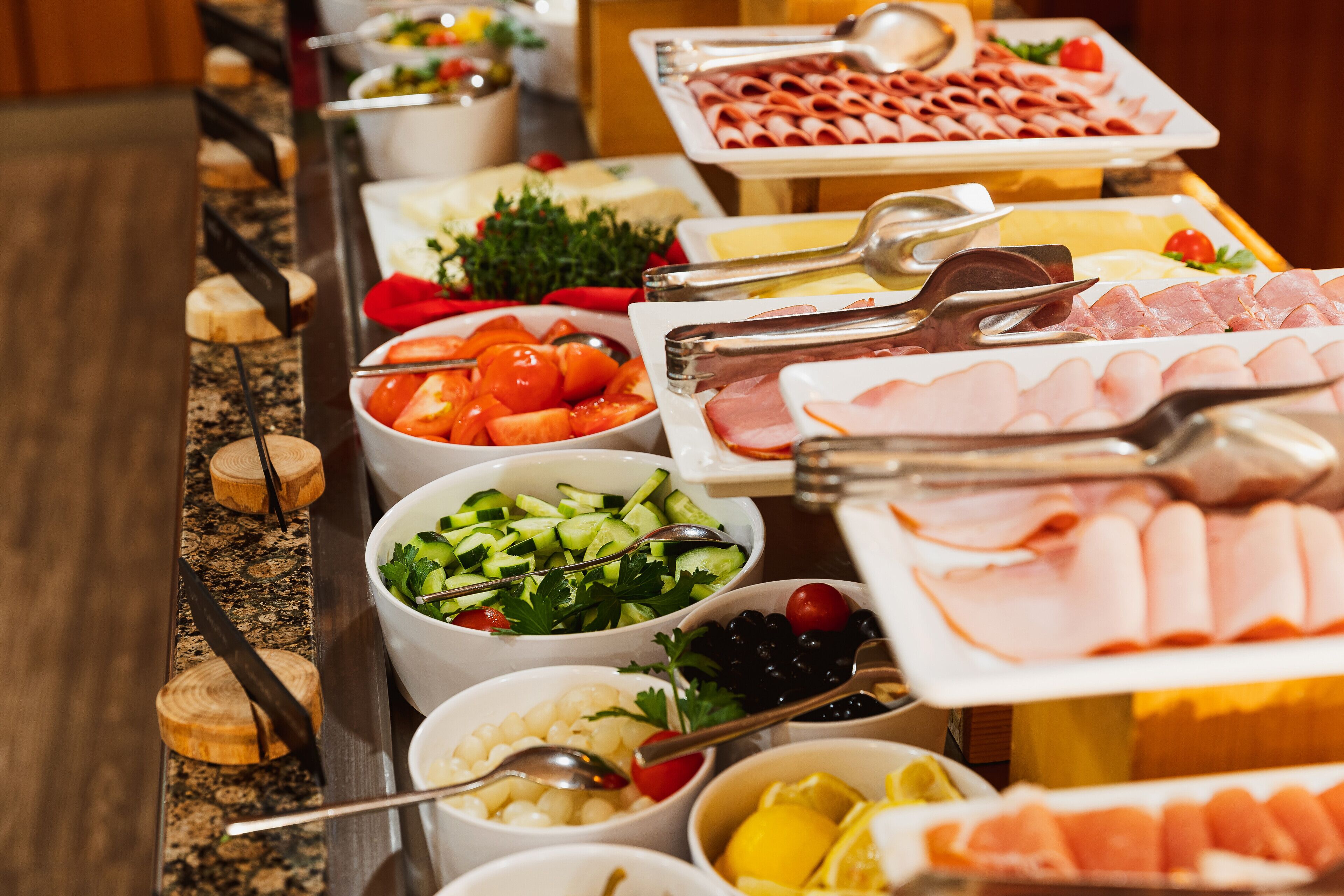 A buffet with various food items including meats, cheeses, fruits, and vegetables.