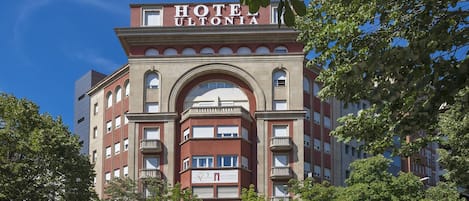 A hotel with a classic architectural style, featuring a prominent arched entrance and multiple balconies.