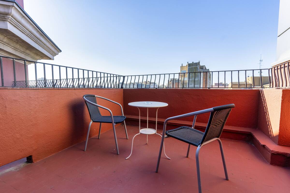 A balcony with two metal chairs and a small round table.