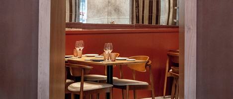 Un interior de restaurante con un área de comedor central, mesas y sillas de madera.