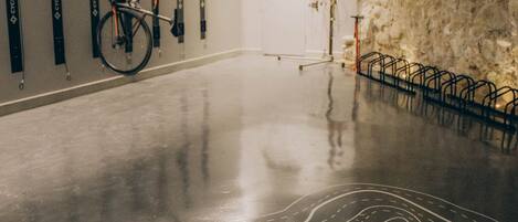 A spacious indoor area with a polished concrete floor, a bicycle mounted on the wall, and a stone wall.