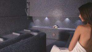 Ein Wellnessraum mit Massage-Sessel, einer kleinen Ablage mit Dekoration und einer Badewanne.