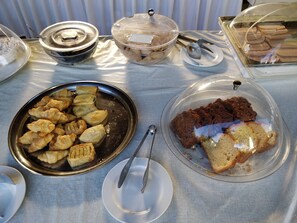 A buffet table with various food items including pastries, bread, and desserts. - Alianthos Suites (Chania)