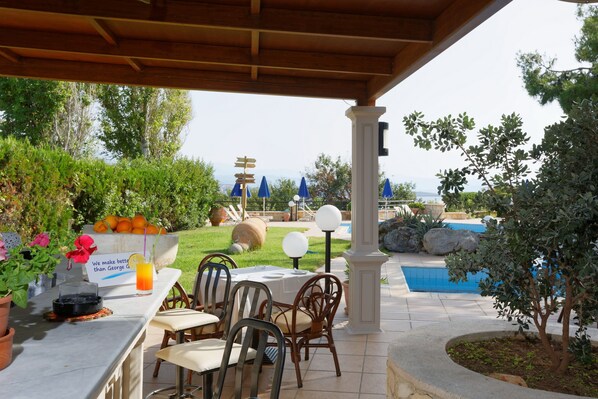 An outdoor patio area with a pool, dining tables, and chairs.