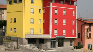 A multi-story hotel with a yellow and red facade, a visible restaurant sign, and a clear entrance.