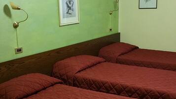 Une pièce avec un mur vert, un lit avec une literie rouge et deux tableaux encadrés.