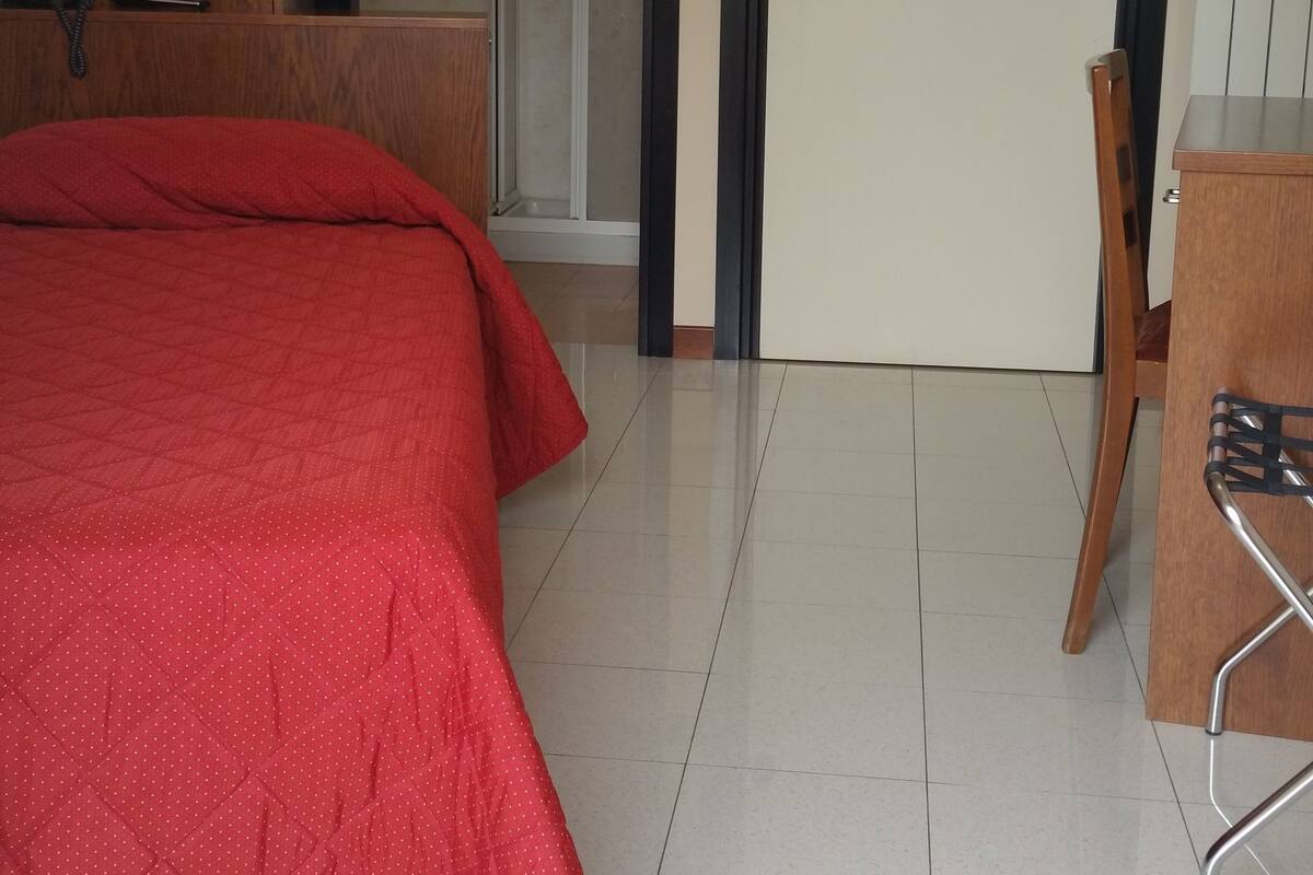 Ein Hotelzimmer mit einem Bett, einem Schreibtisch, einem Stuhl, einem Kleiderschrank und einer Tür.