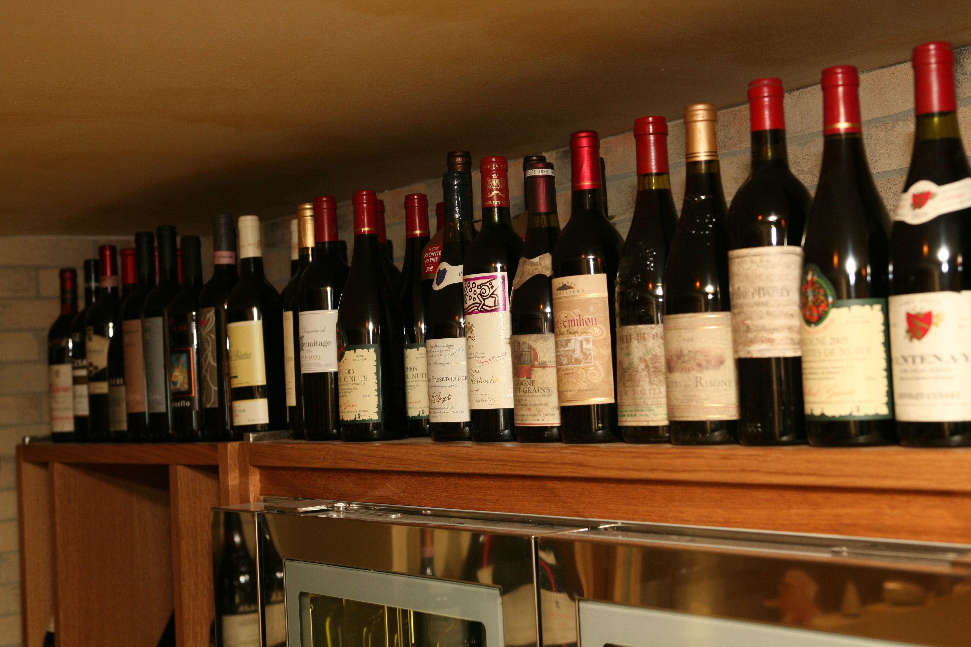 A row of wine bottles on a wooden shelf.