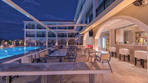 A multi-level outdoor dining area with a pool, bar, and seating. - Athina Apts (Zakynthos)