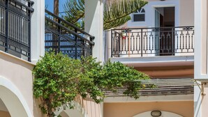 A multi-story building with a central courtyard, featuring a staircase, potted plants, and a balcony. - Athina Apts (Zakynthos)