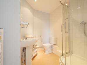 A modern bathroom with a glass shower enclosure, a white sink, and a toilet.